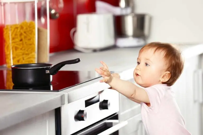 A curious toddler reaching towards a pot on a stove with a look of fascination, highlighting the importance of kitchen safety and child supervision.